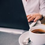 laptop beside mug on table